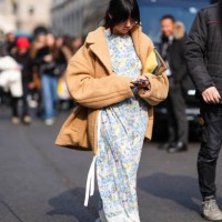 Susie Lau wears a beige wool jacket, a white and blue floral prints dress, a yellow leather bag, outside Onitsuka Tiger , during the Milan Fashion...