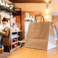 take out food kept in brown paper bag on bar counter during pandemic - junk food stock pictures, royalty-free photos & images