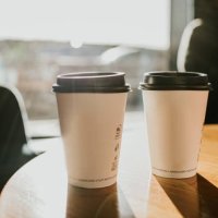 takeaway coffee cups on a wooden table casting long shadows - coffee stock pictures, royalty-free photos & images