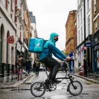 Takeaway food courier, working for Deliveroo, operated by Roofoods Ltd., cycles past food outlets in the Soho district of London, U.K., on Friday,...