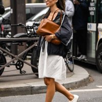Tamara Kalinic is seen wearing a gray Miu Miu top, black Miu Miu jacket, white skirt, white sneakers and brown Miu Miu bag and black sunglasses...