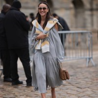 Tamara Kalinic was seen wearing white shoes, a grey dress, dark shades, a beige and grey scarf around her shoulders as well as a brown bag before the...