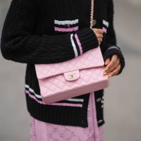 Tamu McPherson wears a black with white and pink embroidered white and pink striped borders pattern buttoned jacket from Chanel, a pale pink shiny...