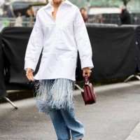 Tamu McPherson wears bordeaux sunglasses, silver hoop earrings, a white oversized shirt with fringes, a bordeaux Gucci leather bag, blue jeans and...