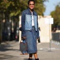 Tamu McPherson wears sunglasses, a bi-color dark blue and pale blue denim jacket, a white t-shirt, a blue slit denim skirt, a bag, black leather...