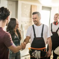 team of happy manual workers welcoming a couple to their apartment. - home decoration stock pictures, royalty-free photos & images