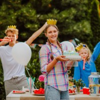 teen girl with crown cap holds birthday cake against her friends background - garden decoration stock pictures, royalty-free photos & images