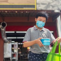 teenage boy buying takeout food from a restaurant using reusable food container - junk food stock pictures, royalty-free photos & images