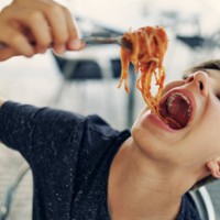 teenage boy enjoying eating spaghetti very much. - food stock pictures, royalty-free photos & images