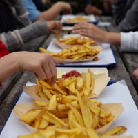 teenagers sitting at a picnic table eating takeaway fast food chips in paper trays - junk food stock pictures, royalty-free photos & images
