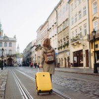 the beautiful cheerful woman with a suitcase walking on an ancient european street in the autumn - travel stock pictures, royalty-free photos & images