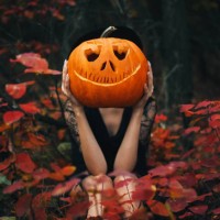 the girl sits in the forest and holds a pumpkin in her hands. halloween pumpkin. autumn background. - fashion stock pictures, royalty-free photos & images