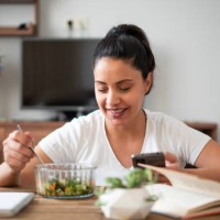 the smiling beautiful woman feeds healthy and using a phone - food stock pictures, royalty-free photos & images