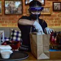 This photo taken on May 4, 2020 shows an employee from the high-end Thai restaurant At-Ta-Rote restaurant packing an order to be delivered by White...