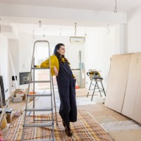 thoughtful woman leaning on ladder in new living room - home decoration stockfoto's en -beelden