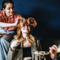 three cheerful friends joking and playing with food during cozy pizza gathering - junk food stock pictures, royalty-free photos & images