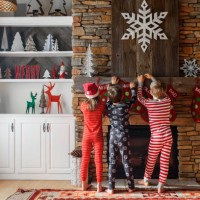 three children hanging up christmas stockings on a fireplace - home decoration stockfoto's en -beelden