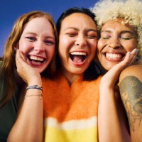 three gen z women laughing together on blue background - fashion stock pictures, royalty-free photos & images