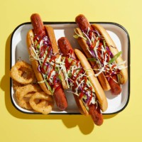 three hotdogs on tray with onion rings, overhead view on yellow background - junk food stock pictures, royalty-free photos & images