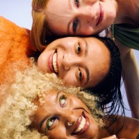 three smiling gen z women resting heads together, embracing wellness and friendship - fashion stock pictures, royalty-free photos & images