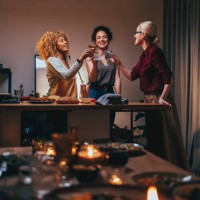 three woman toasting with a glass of wine during a dinner preparation - food stock pictures, royalty-free photos & images