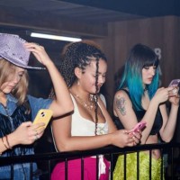 three women looking at their phones at a music event. - concert stock pictures, royalty-free photos & images