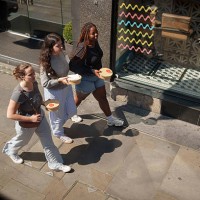 Three work colleagues bring identical takeaway lunches along the street, on 29th April 2025, in London, England.