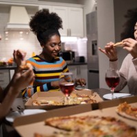 three young beautiful multi-ethnic women having fun at home party - junk food stock pictures, royalty-free photos & images