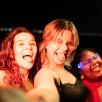 three young women taking selfie sticking out tongues at night - concert stock pictures, royalty-free photos & images