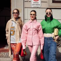 Tiany Kiriloff wears orange skirt, white shirt with the numbers, beige coat and beige scarf and Nina Sandbech wears pink leather matching pants and...