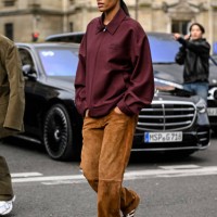 Tina Kunakey is seen wearing a maroon Miu Miu jacket, brown pants and white and black stripe sneakers outside the Miu Miu show during the Womenswear...