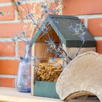 tiny insect house with straws and other garden decor on a wooden shelf. dried flowers, blue glass bottle, dry polypore - garden decoration stock pictures, royalty-free photos & images