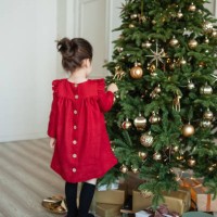 toddler girl in red linen dress and a headband decorates christmas tree at home. christmas outfit. preparing for celebration. festive season. lifestyle portrait. - home decoration stock pictures, royalty-free photos & images
