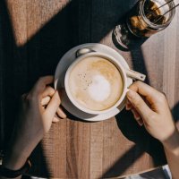 top view of woman sitting by the window in coffee shop enjoying the warmth of sunlight and drinking coffee - coffee stockfoto's en -beelden
