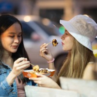 tourist women enjoyment eating snack street food in famous street night marke - junk food stock pictures, royalty-free photos & images