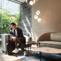 travelling asian businessman on his phone at an airport lounge - travel stock pictures, royalty-free photos & images