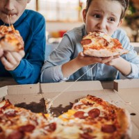 two brothers eating pizza together - junk food stock pictures, royalty-free photos & images