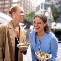 two businesswomen smiling and enjoying healthy bowls outdoors in sydney downtown - junk food stock pictures, royalty-free photos & images