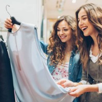 two cheerful girls shopping for clothes - fashion stock pictures, royalty-free photos & images
