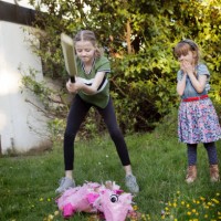 two children hitting a pink pig pinata with a sports bat in a back yard - garden decoration stock pictures, royalty-free photos & images
