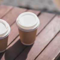 two coffees in paper disposable takeaway cups sit on a wooden table. coffee to take away, take it with you. - junk food stock pictures, royalty-free photos & images