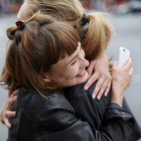 two female friends with cell phone hugging - hairstyle stock-fotos und bilder