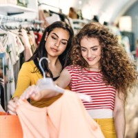 two female teenager friends standing inside in the shop, holding and looking at dress. - fashion stock pictures, royalty-free photos & images