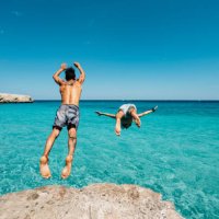 two friends are diving in the sea from a cliff - travel stock pictures, royalty-free photos & images