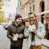 two friends eating fast food outdoors - junk food stock pictures, royalty-free photos & images