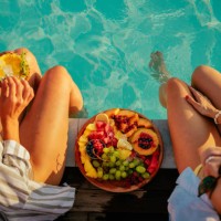 two friends eating fruits by the pool - food stock pictures, royalty-free photos & images