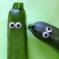 two funny zucchini with cartoon eyes on green background - food stockfoto's en -beelden