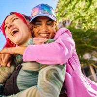 two gen z adults hugging and smiling outdoors in an urban environment. close-up shot. - fashion stock pictures, royalty-free photos & images