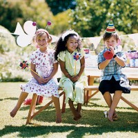 two girls and one boy sitting at a garden table at a birthday party - garden decoration stockfoto's en -beelden