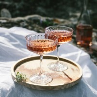 two glasses of rose wine outdoors on wooden tray and white textile, picnic in spring. sunny day, green grass and blossoming cherry trees. - home decoration stock pictures, royalty-free photos & images